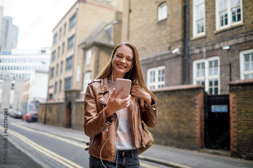 Young woman using a phone while walking in the city london