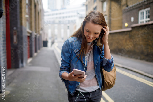 Photography Young woman using a phone while walking in the city london