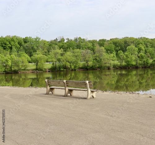 The empty park bench at the lake on a sunny day.