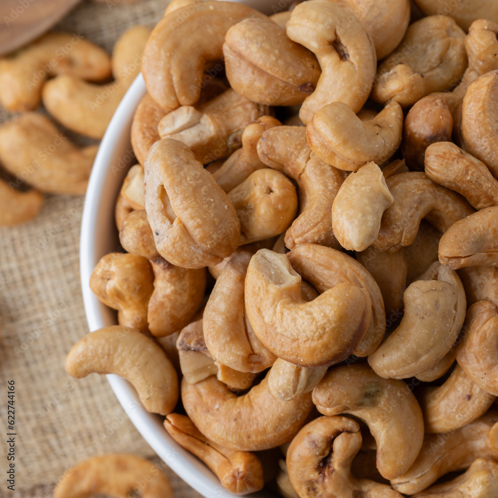 Roasted cashew nuts and halves in wooden bowl on table top view. Macro studio shot Homemade Roasted Salted Cashews in basket and spoon breakfast on sack, Healthy food Seeds snack product Roasted cashew nuts and halves in wooden bowl on table top view. Macro studio shot Homemade Roasted Salted Cashews in basket and spoon breakfast on sack, Healthy food Seeds snack product