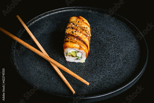 sushi, delicious banana sushi roll with crab, exquisite asian sushi, asian food, sushi on a blue plate on a black background photo