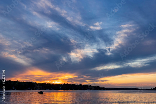 A beautiful sunset on a lake with the silhouette of a boat.