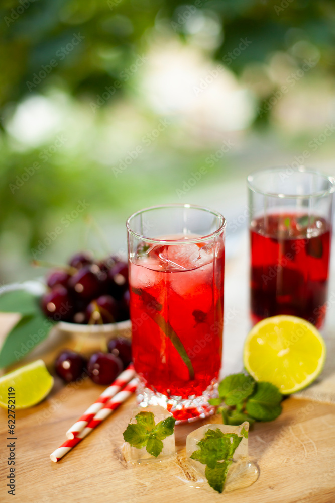 Cherry lemonade with ice and lime in glasses. Summertime cool drink.