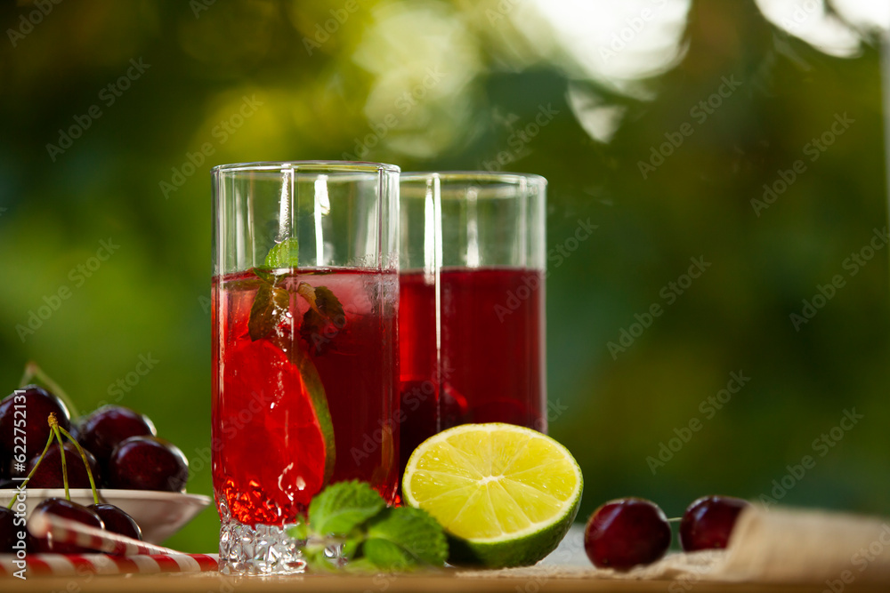 Cherry lemonade with ice and lime in glasses. Summertime cool drink.