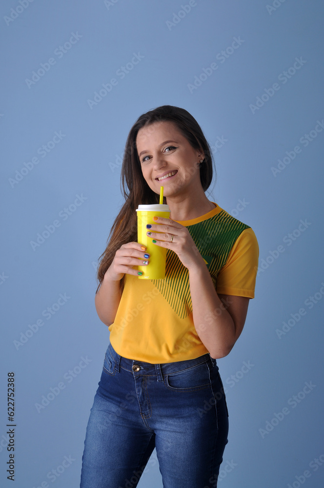 jovem mulher brasileira com camisa do brasil tomando suco ou água , vida saudável jovem mulher brasileira com camisa do brasil tomando suco ou água , vida saudável