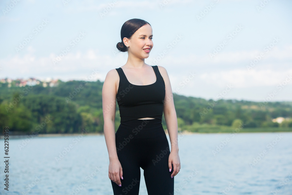 Young woman in black sportswear exercising outdoors. Fitness and healthy lifestyle concept. The white girl does sports in the park. Young woman in black sportswear exercising outdoors. Fitness and healthy lifestyle concept. The white girl does sports in the park.