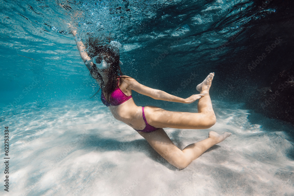 Young woman with mask swimming and fun underwater in transparent ocean.