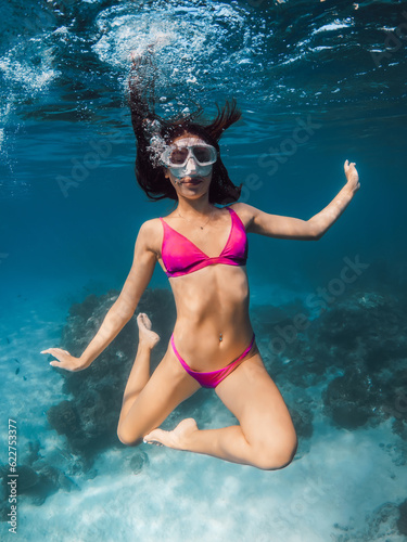 Young woman in bikini fun underwater in transparent ocean.