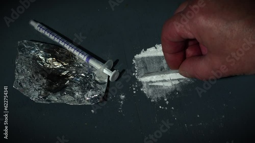 Drug addict preparing lines of heroin for injection photo