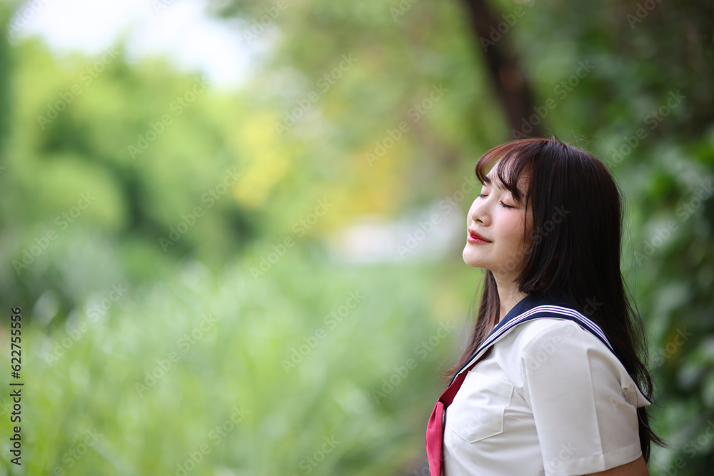 Japanese high school student looking in park with tree background Japanese high school student looking in park with tree background