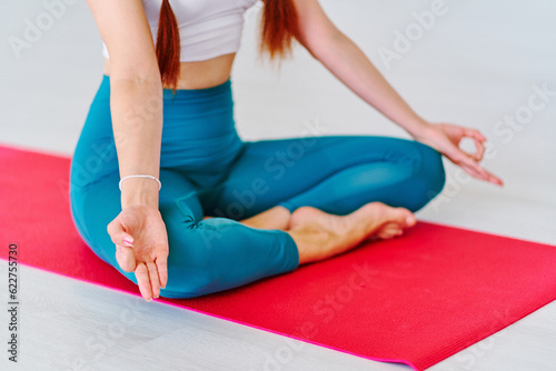 Calm woman with lotus hands pose practices yoga exercise on mat in studio class