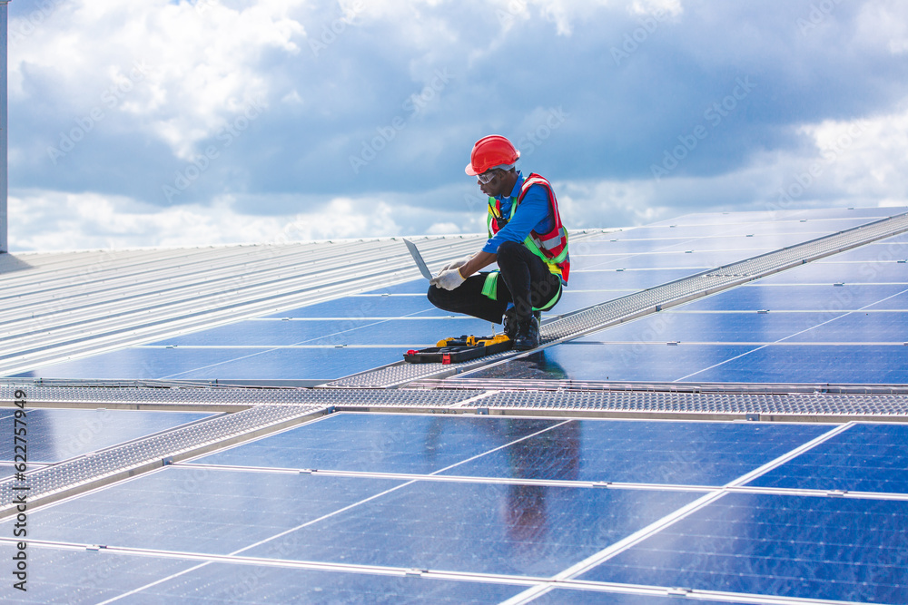 Engineer technician using laptop checking and operating system on rooftop of solar cell farm power plant, Renewable energy source for electricity and power, Solar cell maintenance concept