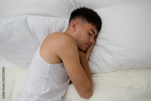 Young Man Sleeping on Top of Bed