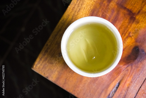 Cold Japanese green tea served in oriental classic cup or ceremic mug. Japanese ocha on wooden table in a restaurant. Asian herbal traditional drinks.