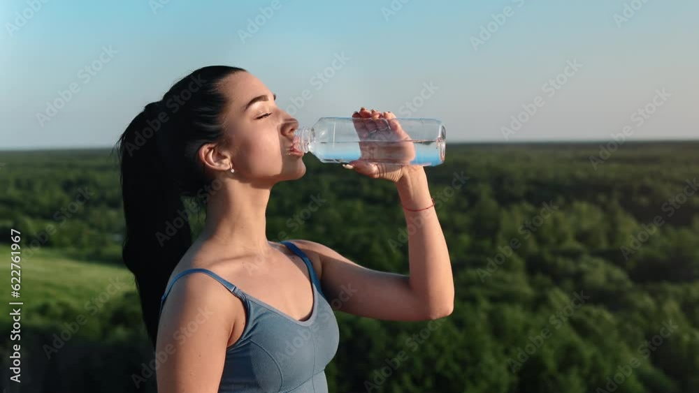 Athletic strong sport woman drinking pure refreshment water from bottle on mountain peak panorama