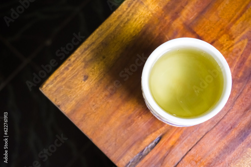 Cold Japanese green tea served in oriental classic cup or ceremic mug. Japanese ocha on wooden table in a restaurant. Asian herbal traditional drinks.