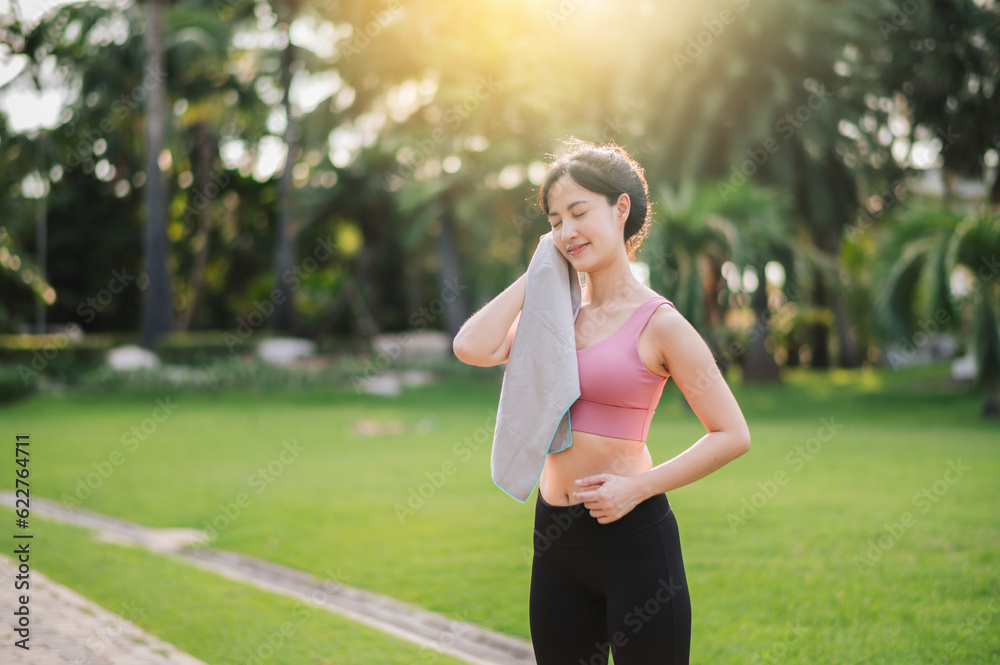 Happy 30s asian woman in pink sportswear wipes her cheek after sunset workout in nature. Captures beauty of healthy lifestyle and perfect for project promoting fitness, health, or motivation. Happy 30s asian woman in pink sportswear wipes her cheek after sunset workout in nature. Captures beauty of healthy lifestyle and perfect for project promoting fitness, health, or motivation.