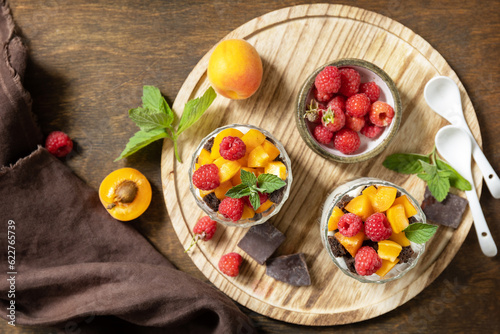 Triffle of chocolate biscuit with yogurt and fresh berries and fruits. Two portioned glass parfafait dessert. Summer healthy diet breakfast, snack concept. View from above. photo