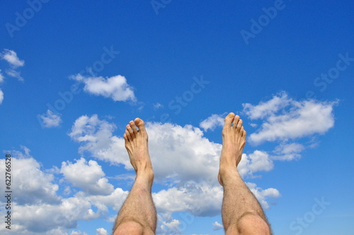 Business person jumping over clouds in the blue sky.