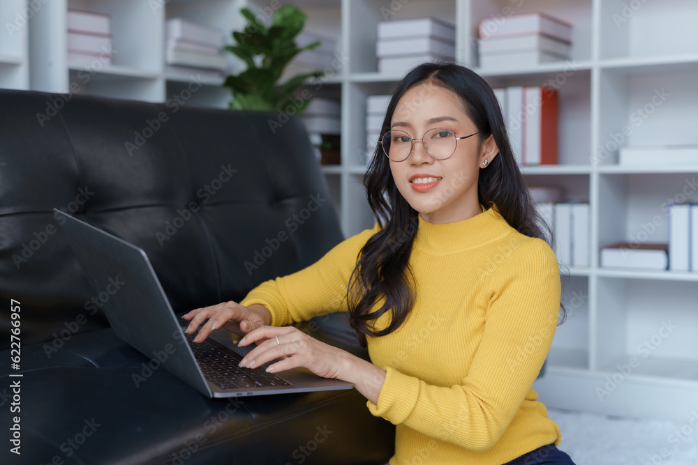 Cute Asian young woman using laptop computer in the living room, watching movie, listening to music, shopping online, watching live broadcast. Cute Asian young woman using laptop computer in the living room, watching movie, listening to music, shopping online, watching live broadcast.