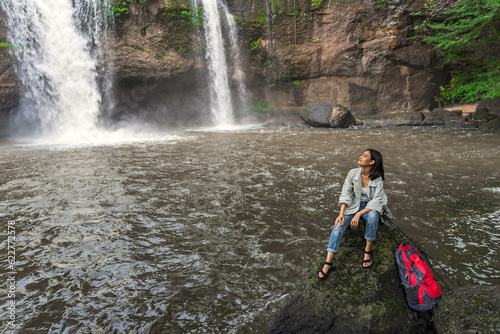 Asian female tourists  trekking  experience the atmosphere of Haew Suwat Waterfall in tropical forest. Khao Yai National Park  Thailand. Young Asian woman trekking to see waterfall in middle of forest