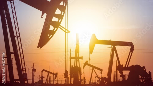 The sun rises behind a large oil field in California.