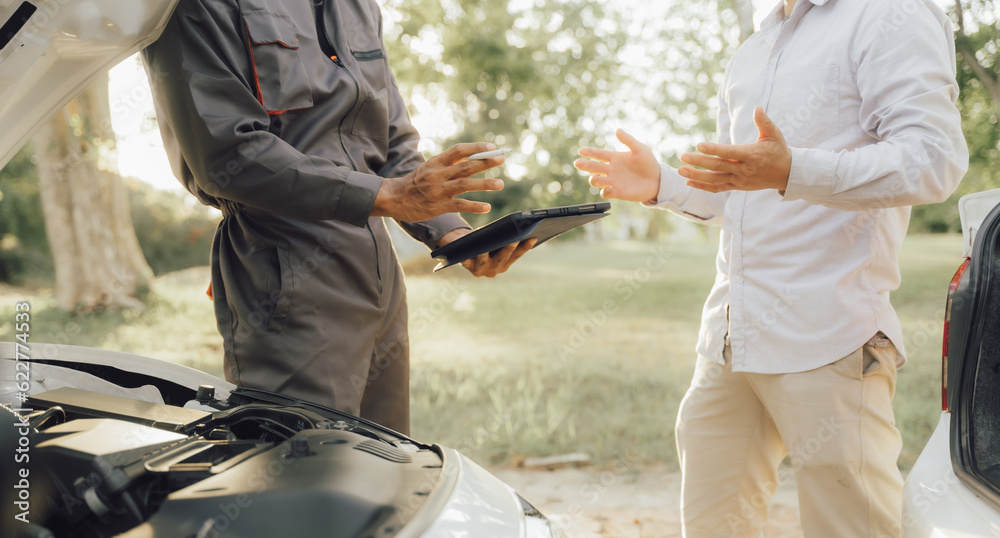 Naklejka premium Young mechanic opens the bonnet to inspect the engine for damage and does professional maintenance. He puts on his uniform and inspects.