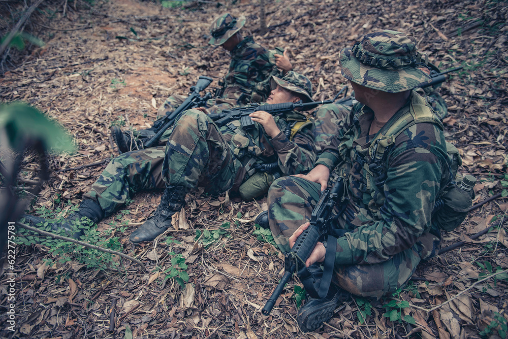 Team of army soldier with machine gun moving in the forest,Thai militia soldier in combat uniforms in the wood,Wander the patrol sloping in the rainforest.