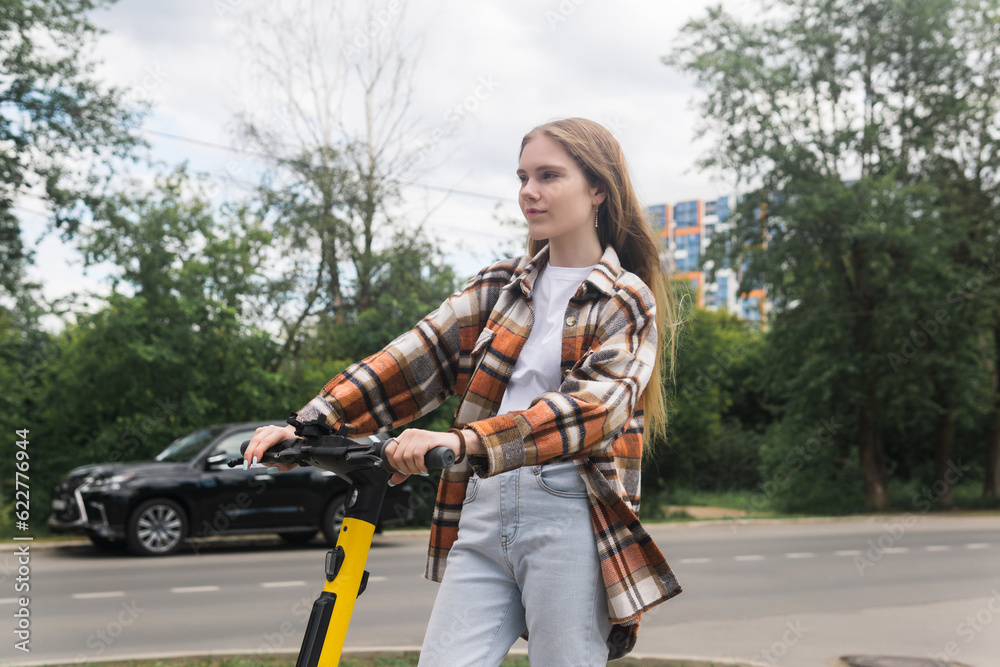 young woman on an electric scooter rides down the street