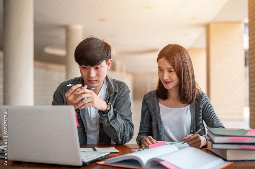 Two students are sitting at table reading books to education. Study for test preparation in University. Two students are sitting at table reading books to education. Study for test preparation in University.