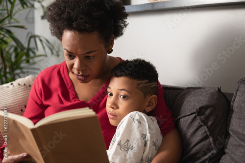 Doting mother reads book to young son in home room