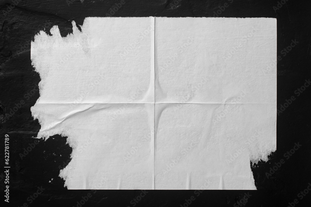 White paper with folds on a black wall.