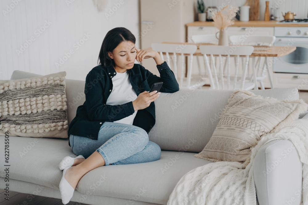 Modern woman uses mobile apps at home, leisurely browsing on couch. Focused on social networks, messaging, news, and online shopping. Modern woman uses mobile apps at home, leisurely browsing on couch. Focused on social networks, messaging, news, and online shopping.