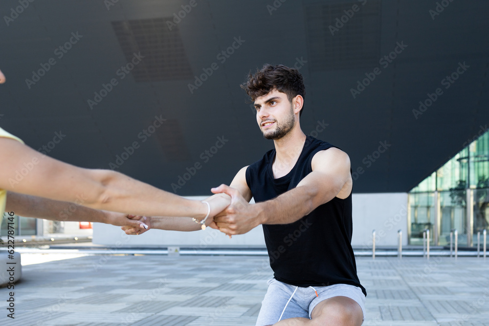 Happy young man with stretched arms holding hands of unrecognizable woman