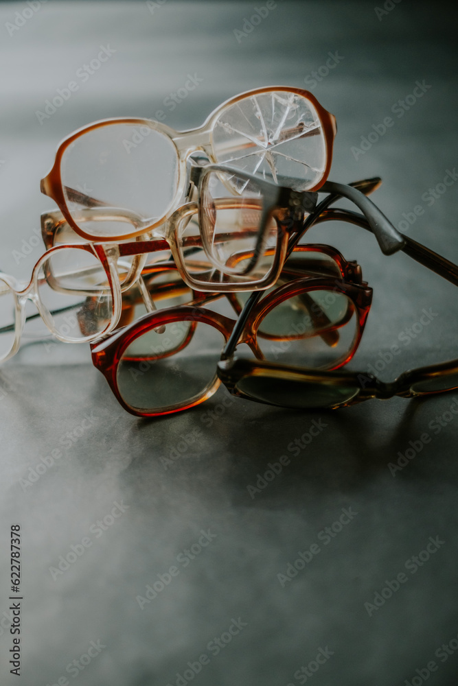 Stack of broken eyeglasses on smooth grey floor Stack of broken eyeglasses on smooth grey floor