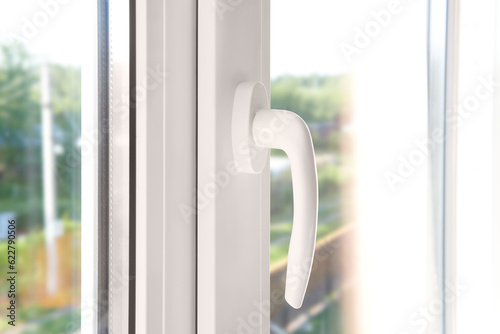 White plastic window handle. Plastic window furniture close-up.