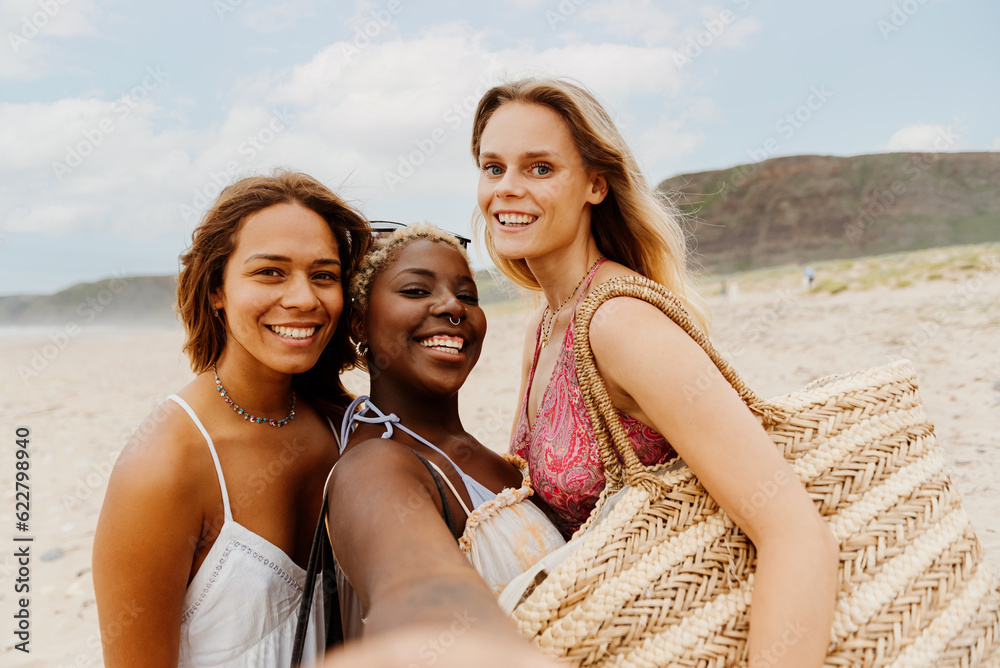 multiracial group of young girls taking a selfie on the beach. Girl friends having a good time during summer vacation. friendship and unity. creating memories.