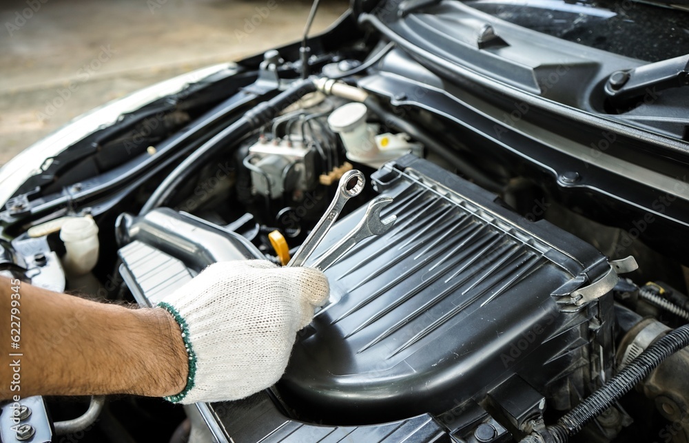 Auto mechanic using wrench to repair car engine.Male hand holding a wrench to repair a car engine Auto mechanic using wrench to repair car engine.Male hand holding a wrench to repair a car engine