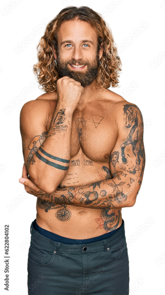 Fototapeta premium Handsome man with beard and long hair standing shirtless showing tattoos with hand on chin thinking about question, pensive expression. smiling and thoughtful face. doubt concept.