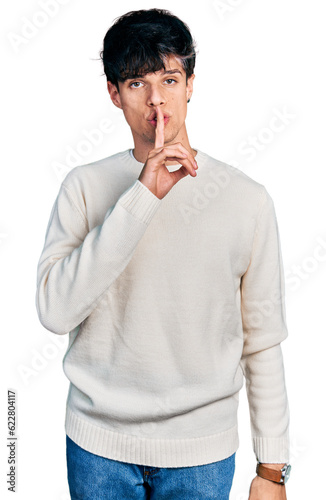 Handsome hipster young man wearing casual winter sweater asking to be quiet with finger on lips. silence and secret concept.