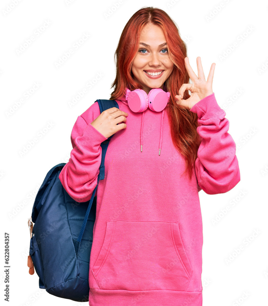 Young redhead woman holding student backpack and books doing ok sign with fingers, smiling friendly gesturing excellent symbol Young redhead woman holding student backpack and books doing ok sign with fingers, smiling friendly gesturing excellent symbol