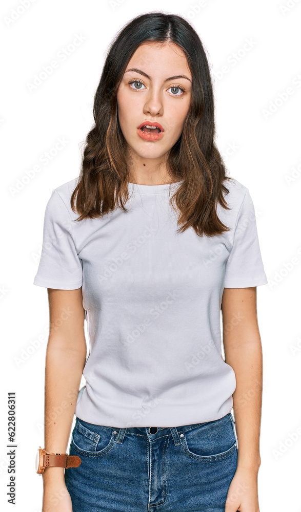 Young beautiful woman wearing casual white t shirt in shock face, looking skeptical and sarcastic, surprised with open mouth Young beautiful woman wearing casual white t shirt in shock face, looking skeptical and sarcastic, surprised with open mouth