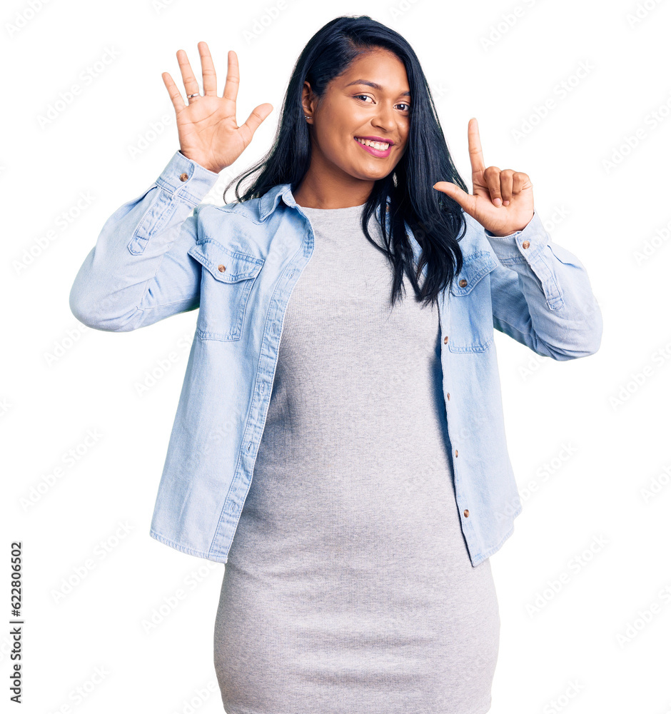 Hispanic woman with long hair wearing casual denim jacket showing and pointing up with fingers number seven while smiling confident and happy. Hispanic woman with long hair wearing casual denim jacket showing and pointing up with fingers number seven while smiling confident and happy.