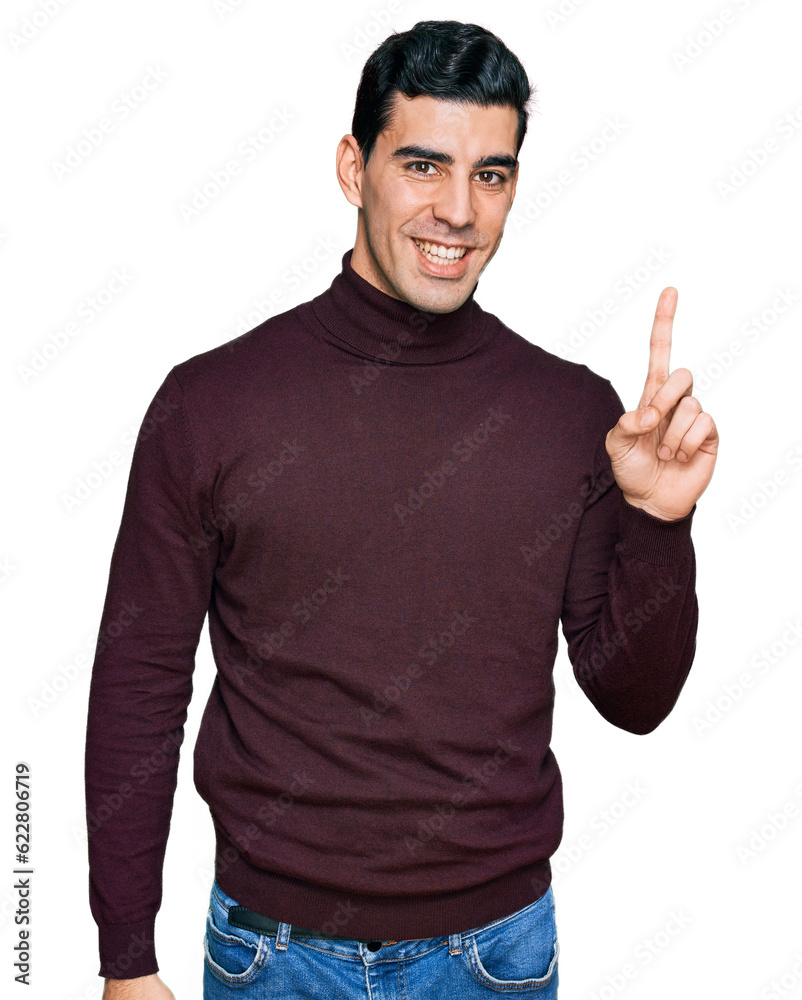Handsome hispanic man wearing casual turtleneck sweater showing and pointing up with finger number one while smiling confident and happy.