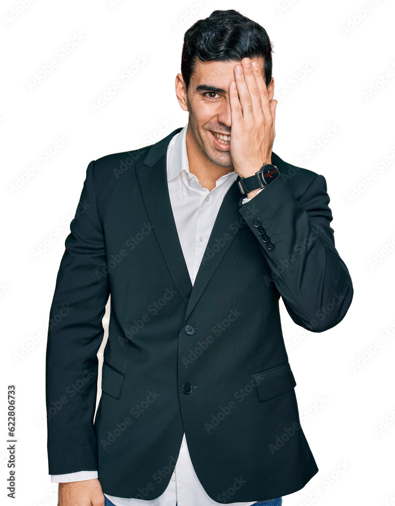 Handsome hispanic man wearing business clothes covering one eye with hand, confident smile on face and surprise emotion. Handsome hispanic man wearing business clothes covering one eye with hand, confident smile on face and surprise emotion.