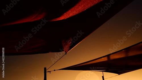 Low angle shot of sails blowing in stormy wind on waterfront at sunset -4K