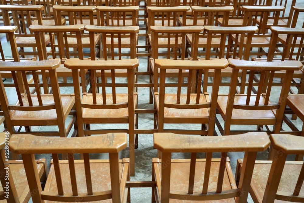Rows of Wooden Brown Chairs on a stone floor. 