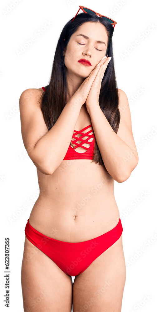 Naklejka premium Young beautiful caucasian woman wearing bikini sleeping tired dreaming and posing with hands together while smiling with closed eyes.