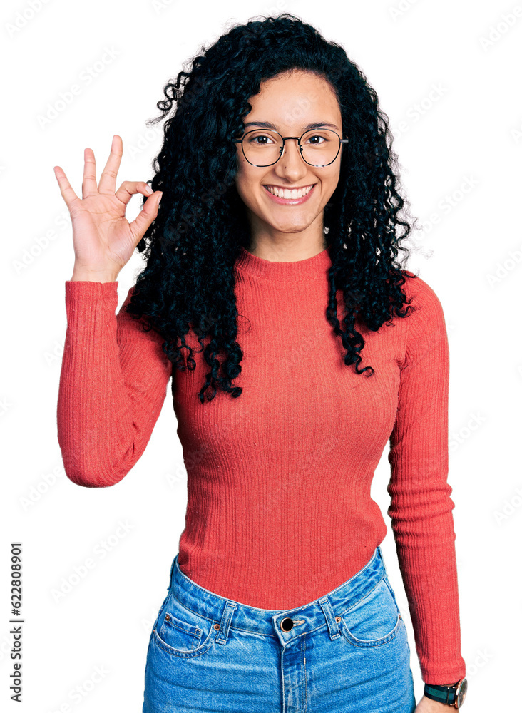 Young hispanic woman with curly hair wearing glasses smiling positive doing ok sign with hand and fingers. successful expression. Young hispanic woman with curly hair wearing glasses smiling positive doing ok sign with hand and fingers. successful expression.