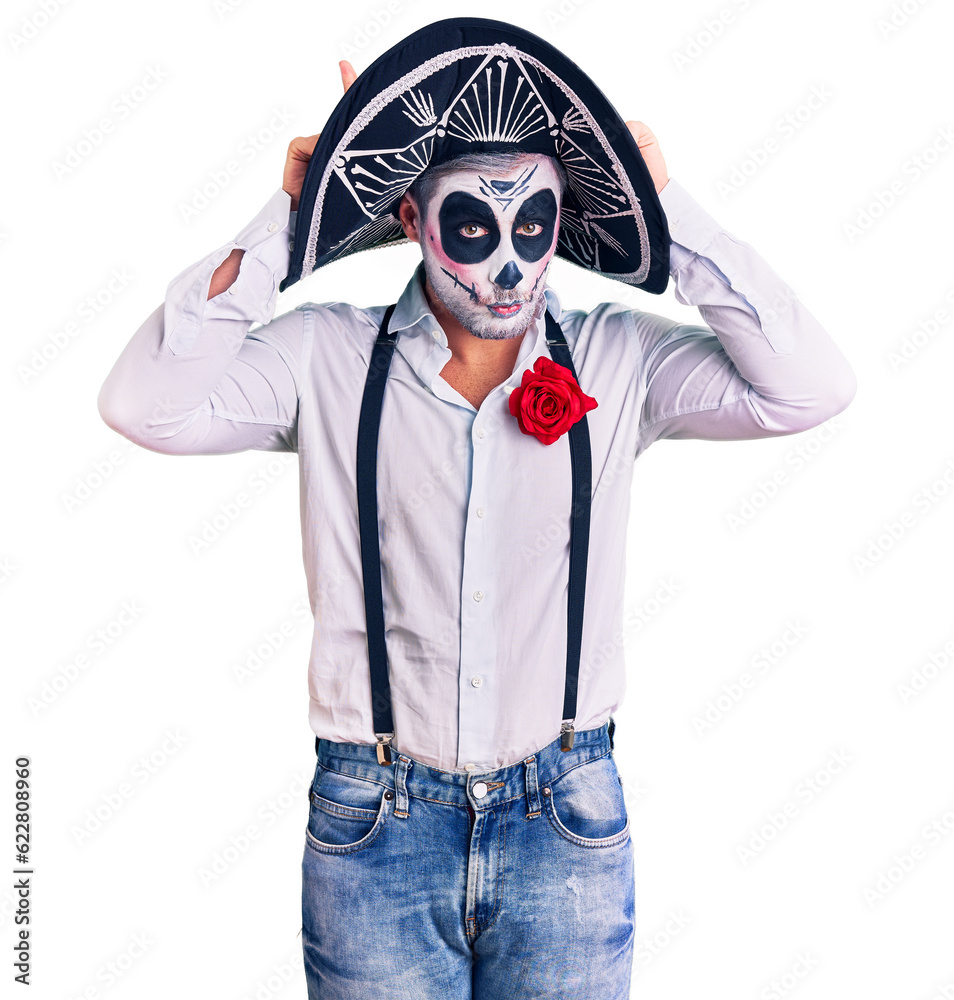 Man wearing day of the dead costume over background doing funny gesture with finger over head as bull horns
